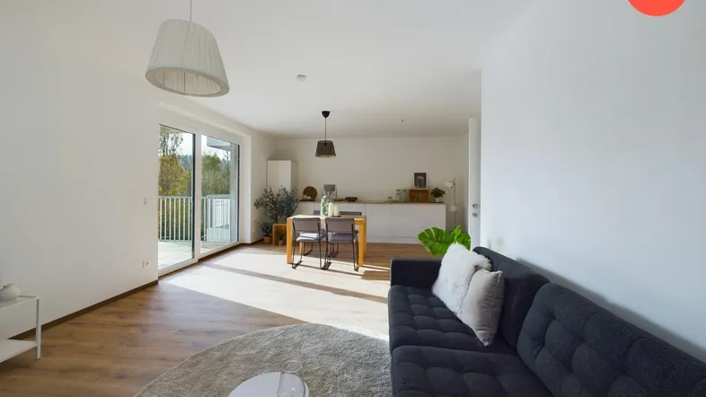 Helles, offenes Wohn- und Esszimmer mit Holzboden und Zugang zu einem Balkon.