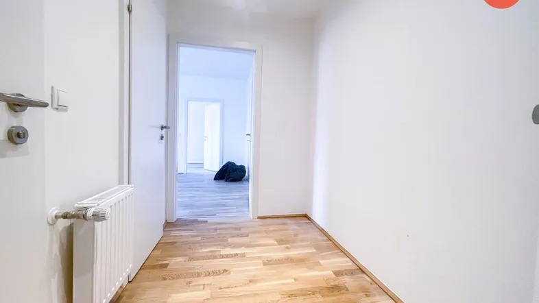 Heller Flur mit Holzparkettboden und Zugang zu weiteren Räumen, ausgestattet mit einem Heizkörper.