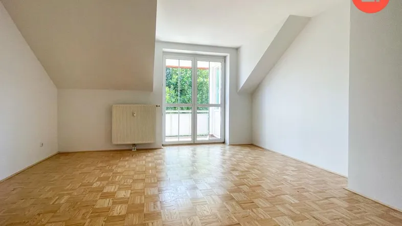 Helles Zimmer im Dachgeschoss mit Parkettboden, Dachschrägen und Zugang zu einem französischen Balkon.