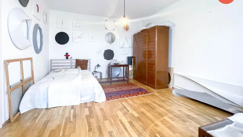 Helles Schlafzimmer mit Holzboden, einem Bett und einem großen Kleiderschrank.