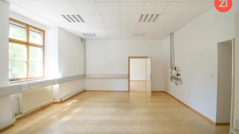 Helles Büro mit Fischgrätparkett, großen Fenstern und abgehängter Decke, ideal für Arbeitsbereiche.