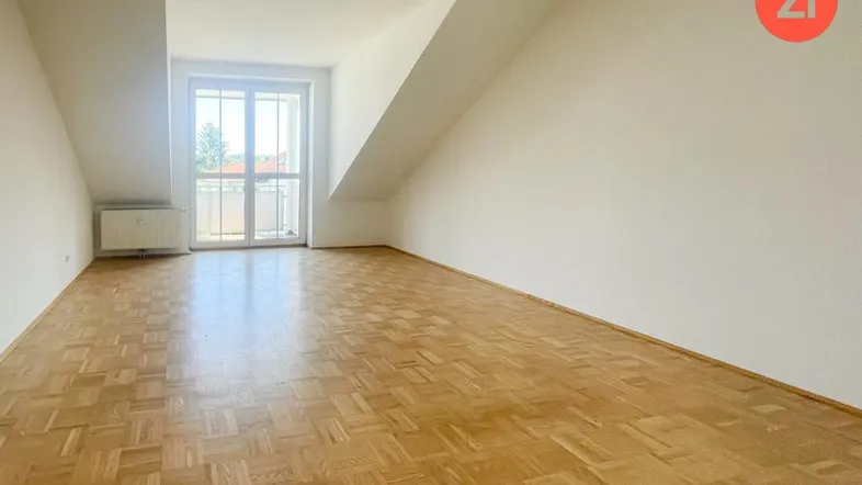 Helles Zimmer mit Parkettboden, Dachschrägen und Zugang zu einem französischen Balkon.
