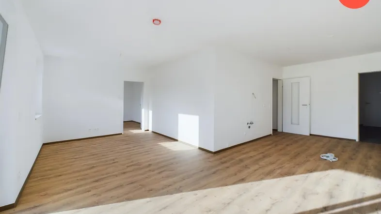 Heller, leerer Wohnbereich mit Laminatboden und weißen Wänden, bereit zur individuellen Gestaltung.