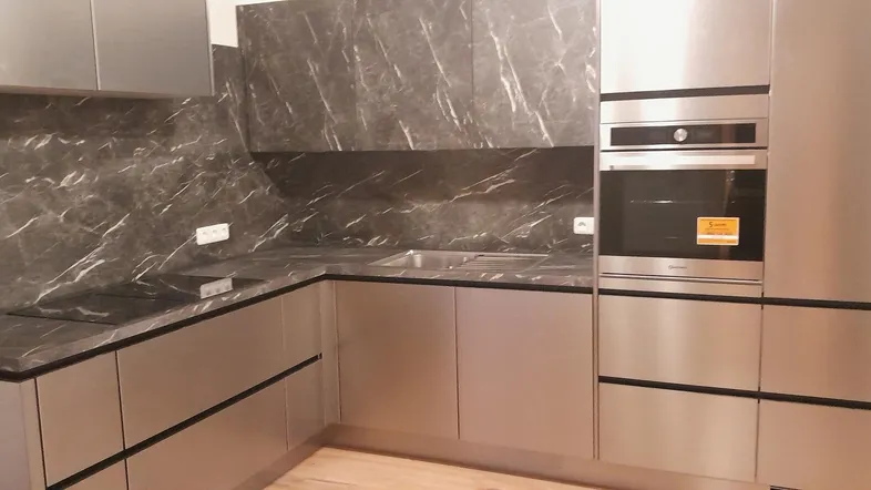 Moderne Einbauküche mit dunklen Marmorarbeitsplatten und integrierten Edelstahlgeräten.