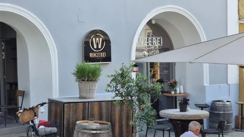 Außenbereich einer Winzerei mit Schirmen, Tischen und Stühlen für Gäste.