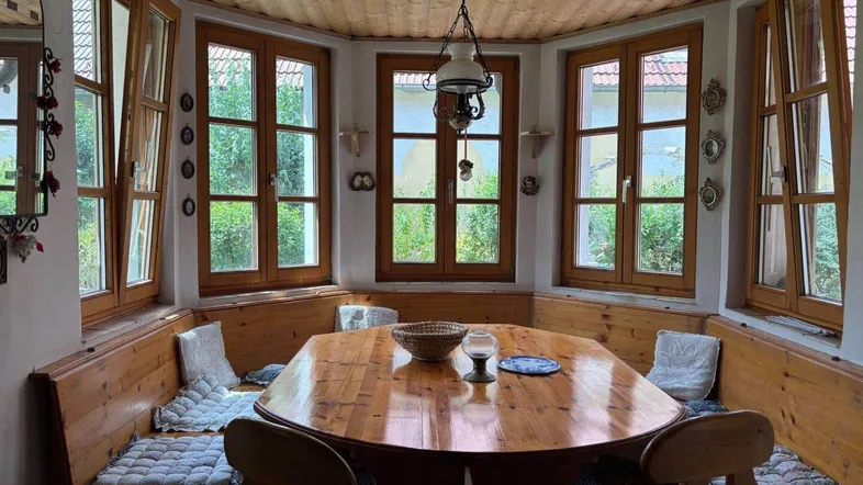 Gemütlicher Essbereich mit Holztisch, Eckbank und vielen Fenstern für natürliches Licht.