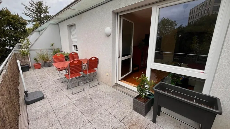 Geräumige Terrasse mit Fliesenboden, Gartenmöbeln und Blick ins Grüne.