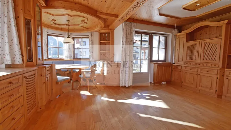 Gemütlicher Wohn- und Essbereich im alpinen Stil mit viel Holz und natürlichem Licht.