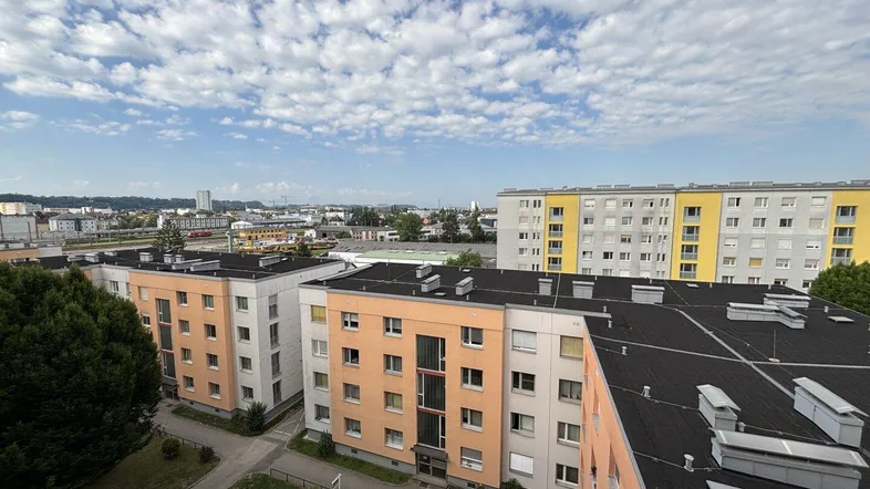 Weitläufige Ansicht von Wohngebäuden mit orangefarbenen und gelben Fassaden unter blauem Himmel.