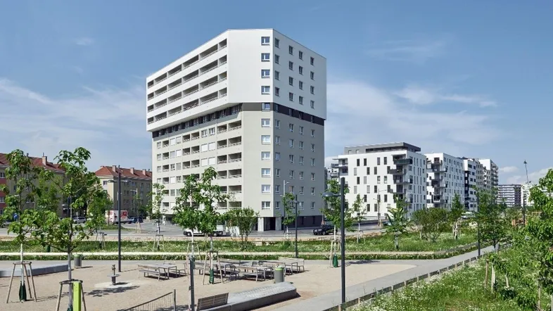 Modernes Wohngebäude mit vielen Balkonen und Grünflächen in städtischer Umgebung.