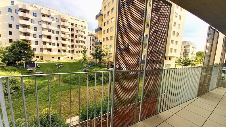 Geräumiger Balkon mit Blick auf die grüne Innenhofanlage und moderne Wohngebäude.