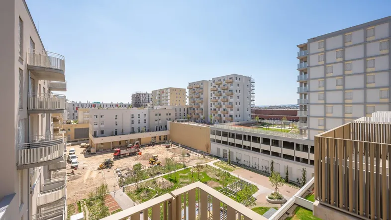 Blick vom Balkon auf einen Innenhof mit Baustelle und moderne Wohngebäude in der Umgebung.