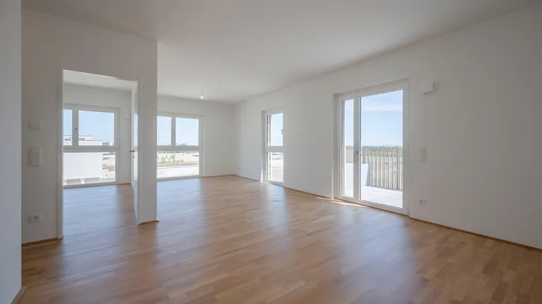 Helles und geräumiges Wohnzimmer mit Parkettboden und Zugang zu einem Balkon oder einer Terrasse.
