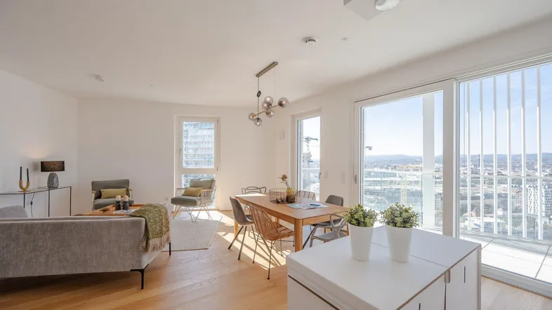 Helles, offenes Wohn- und Esszimmer mit Holzboden und Zugang zum Balkon mit Stadtblick.