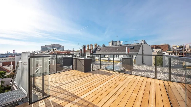 Geräumige Dachterrasse mit Holzboden und Glasgeländer bietet einen weiten Blick über die Stadt.