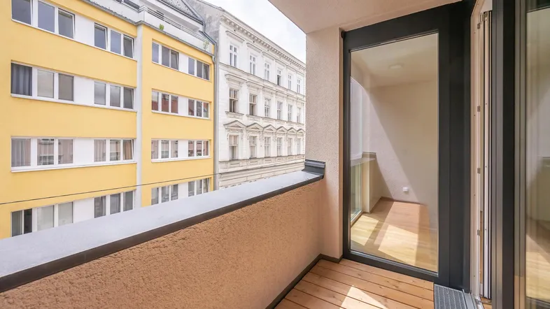 Heller Balkon mit Holzboden und Blick auf die umliegenden Gebäude.