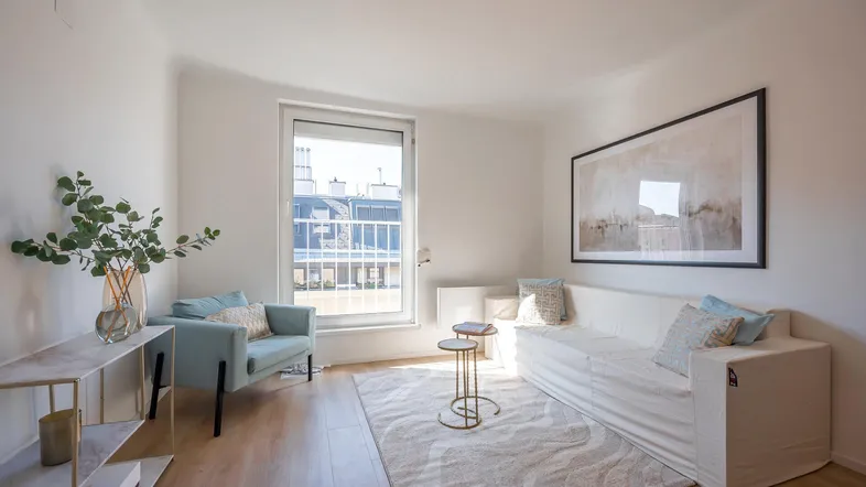 Helles Wohnzimmer mit modernem Sofa, Sessel und Blick auf die Dächer der Stadt.