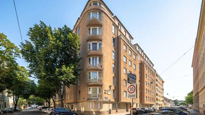 Gebäude mit geschwungener Fassade, Balkonen und Straßenansicht in urbaner Umgebung.
