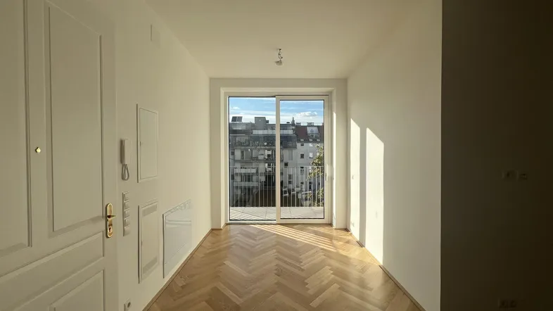 Heller Wohnraum mit Fischgrätparkett und Zugang zu einem Balkon, der einen Stadtblick bietet.