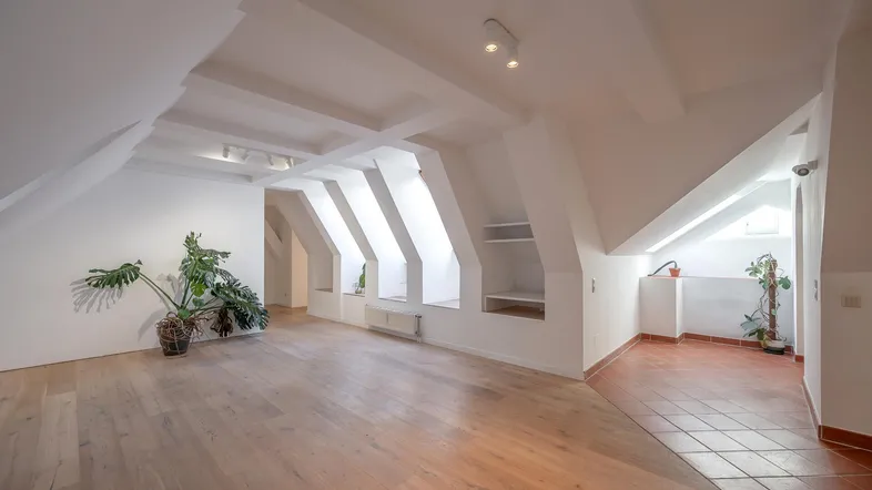 Geräumiges Dachgeschoss-Wohnzimmer mit Holzboden, Dachfenstern und viel Tageslicht.