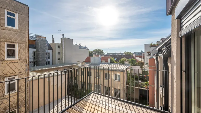 Balkon mit Blick auf die umliegenden Gebäude und sonnigem Himmel über der Stadt.