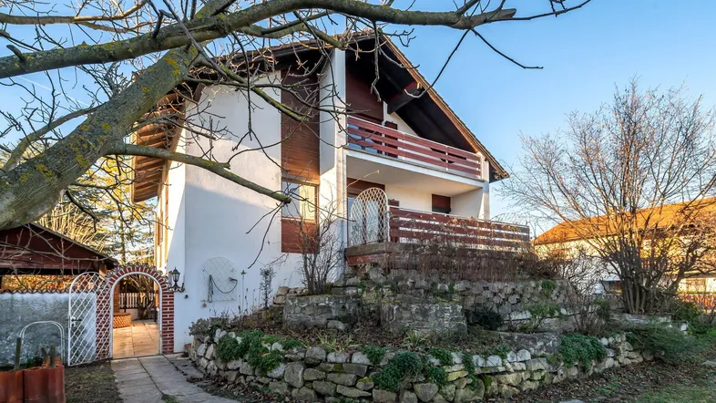 Detailansicht des Hauses mit Balkon, einer Steinmauer und einem charmanten Torbogen.