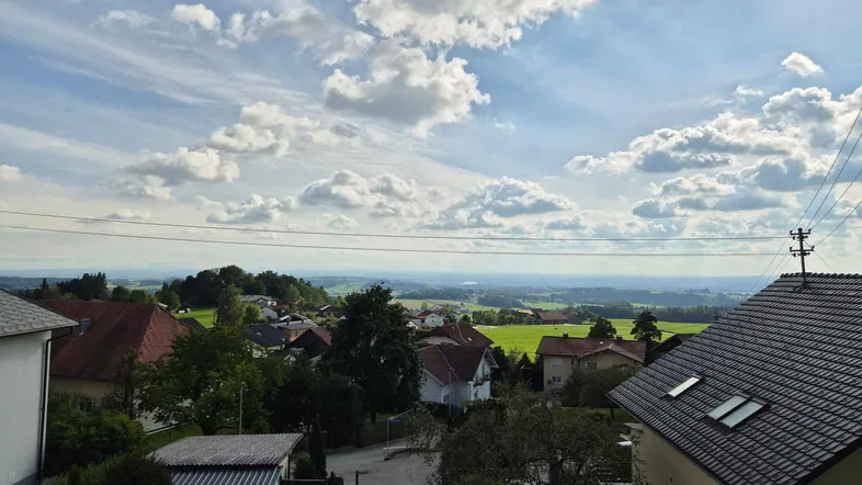 Weitläufiger Blick über die ländliche Umgebung mit Häusern, grünen Feldern und weitem Horizont.