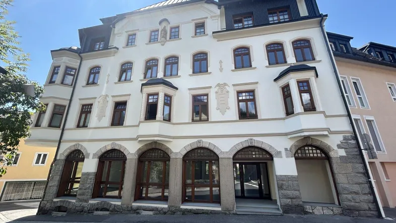 Klassisches Mehrfamilienhaus mit eleganter Fassade, großen Bogenfenstern im Erdgeschoss und Erkern.
