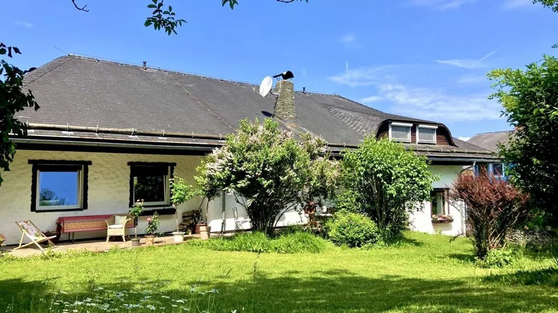 Großzügiger Gartenbereich mit Rasenfläche und blühenden Sträuchern vor dem Landhaus.