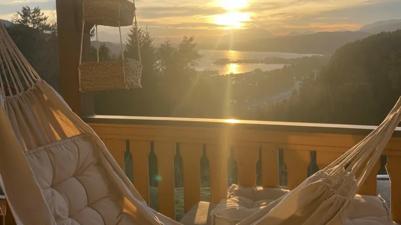 Gemütlicher Balkon mit Hängematte und atemberaubendem Seeblick bei Sonnenuntergang.
