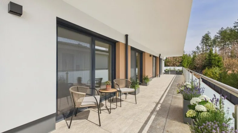 Langer, gefliester Balkon mit Sitzgelegenheiten und Pflanzen, ideal zum Entspannen im Freien.