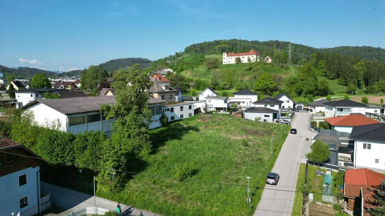 Luftaufnahme eines Baugrundstücks in einer ruhigen Wohngegend mit Blick auf die umliegende Landschaft.