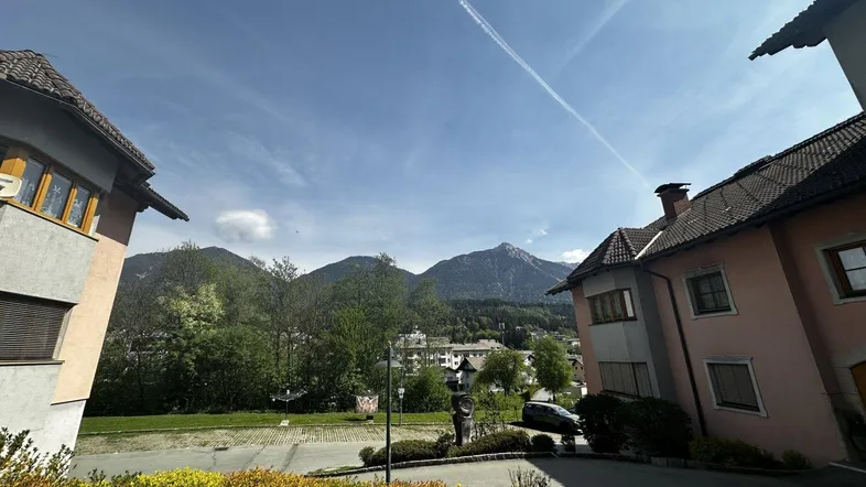 Weitläufiger Blick auf die umliegende Berglandschaft und benachbarte Gebäude unter blauem Himmel.