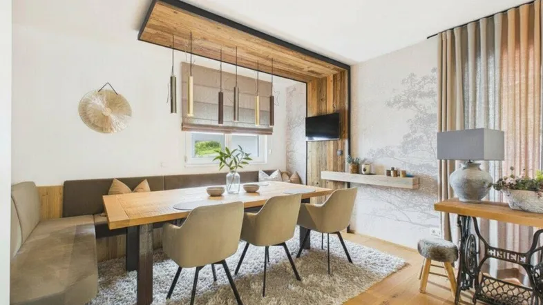 Gemütlicher Essbereich mit Holztisch, Eckbank und moderner Beleuchtung, umgeben von rustikalen Holzelementen.