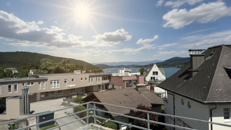 Panoramablick von einer Dachterrasse auf einen See und die umliegende Berglandschaft unter strahlendem Sonnenschein.