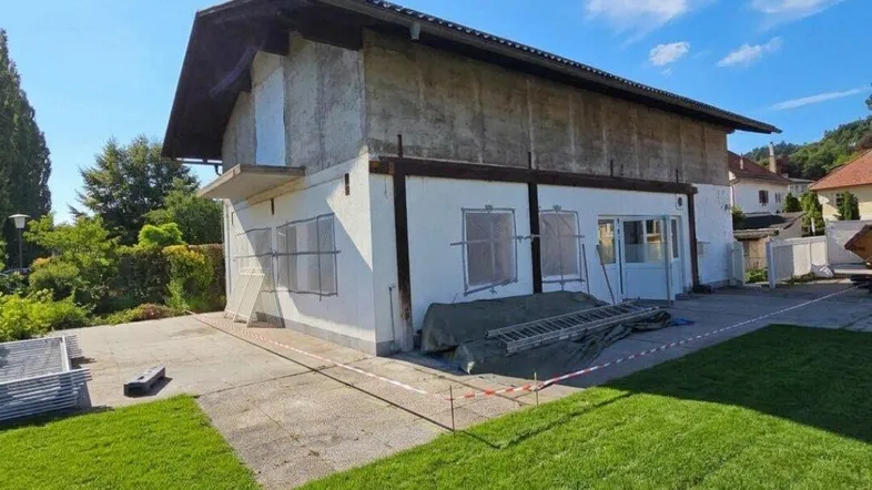 Außenansicht eines Hauses im Rohbauzustand mit Rasenfläche im Vordergrund.