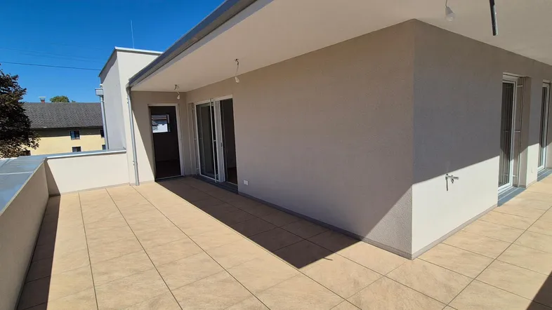 Große, geflieste Terrasse mit Schiebetüren und Blick auf die Umgebung, ideal für Entspannung im Freien.