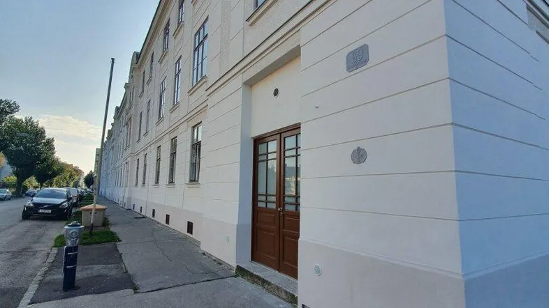 Fassade eines Mehrfamilienhauses mit klassischer Architektur und Holztüren am Eingangsbereich.