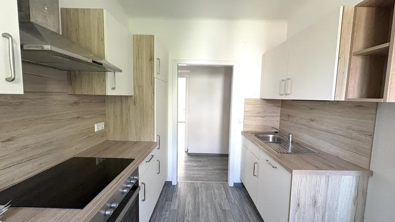 Moderne Küche mit hellen Schränken, Holzoptik-Arbeitsplatten und integrierten Geräten.