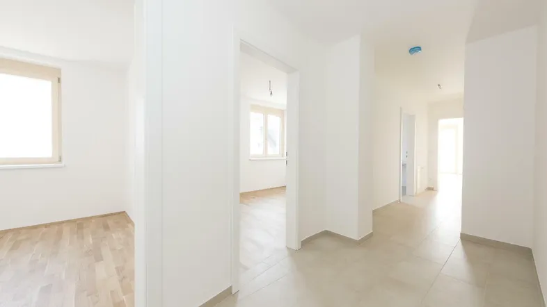 Heller Flur mit modernen Fliesen und Zugang zu weiteren Zimmern mit Parkettboden.