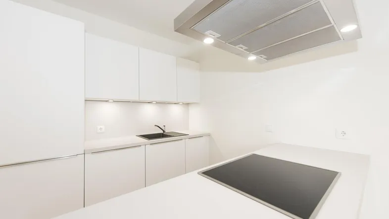 Moderne, helle Küche mit weißen Schränken, Kochinsel und Dunstabzugshaube.