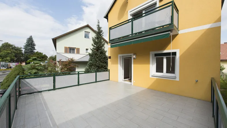 Geräumige Terrasse mit Fliesenboden und Blick auf die Umgebung, ideal für Entspannung im Freien.