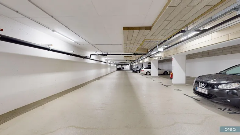 Geräumige und gut beleuchtete Tiefgarage mit mehreren Stellplätzen für Fahrzeuge.