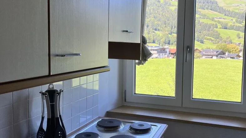Küche mit Kochfeld, weißen Schränken und einem schönen Blick auf die grüne Landschaft.