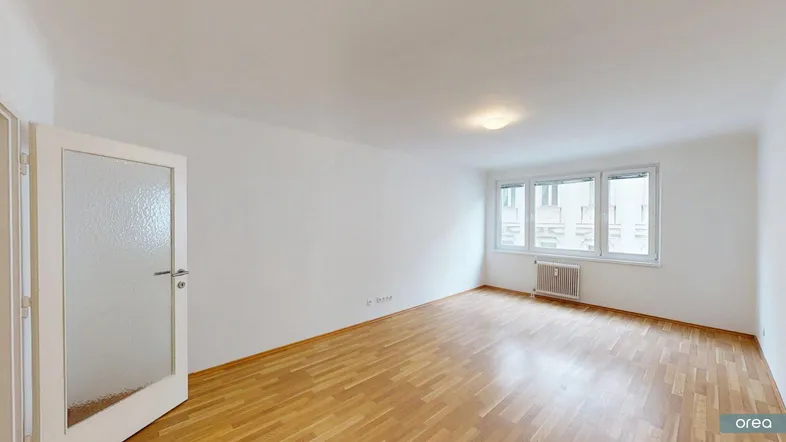Helles, leeres Zimmer mit Parkettboden und weißen Wänden, bereit zur individuellen Gestaltung.