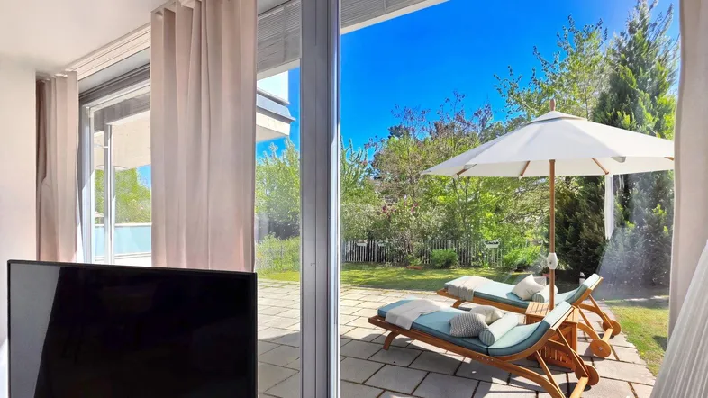 Helles Wohnzimmer mit Zugang zur Terrasse und Blick in den grünen Garten.