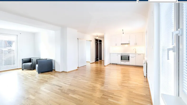 Helles Wohn- und Esszimmer mit offener Küche, Parkettboden und Zugang zu einem Balkon.