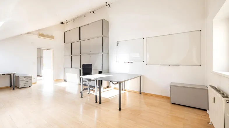 Helles und geräumiges Büro im Dachgeschoss mit schrägen Wänden, Holzfußboden und modernen Büromöbeln.