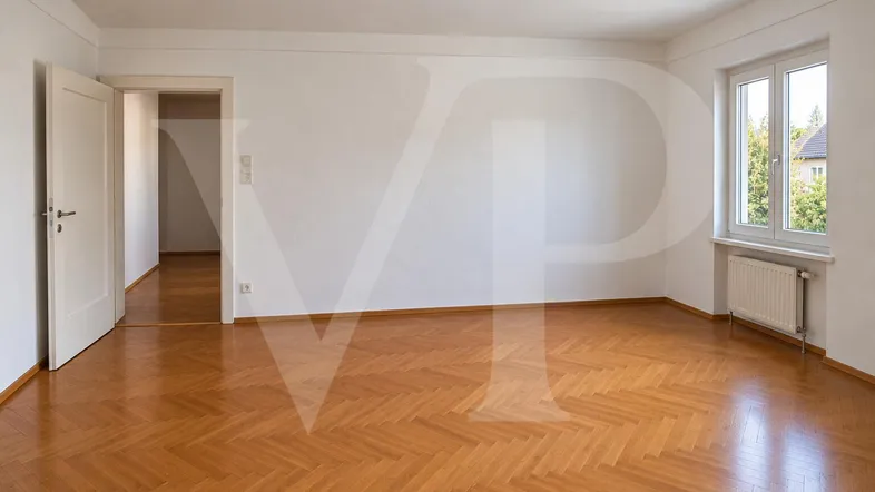 Helles Zimmer mit Fischgrätparkettboden, weißen Wänden und Blick ins Grüne durch das Fenster.