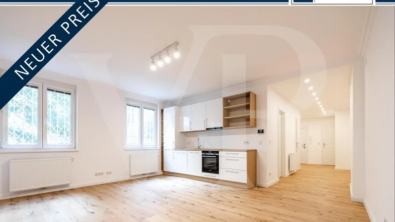 Heller offener Wohnbereich mit integrierter Küchenzeile, Holzboden und großen Fenstern.